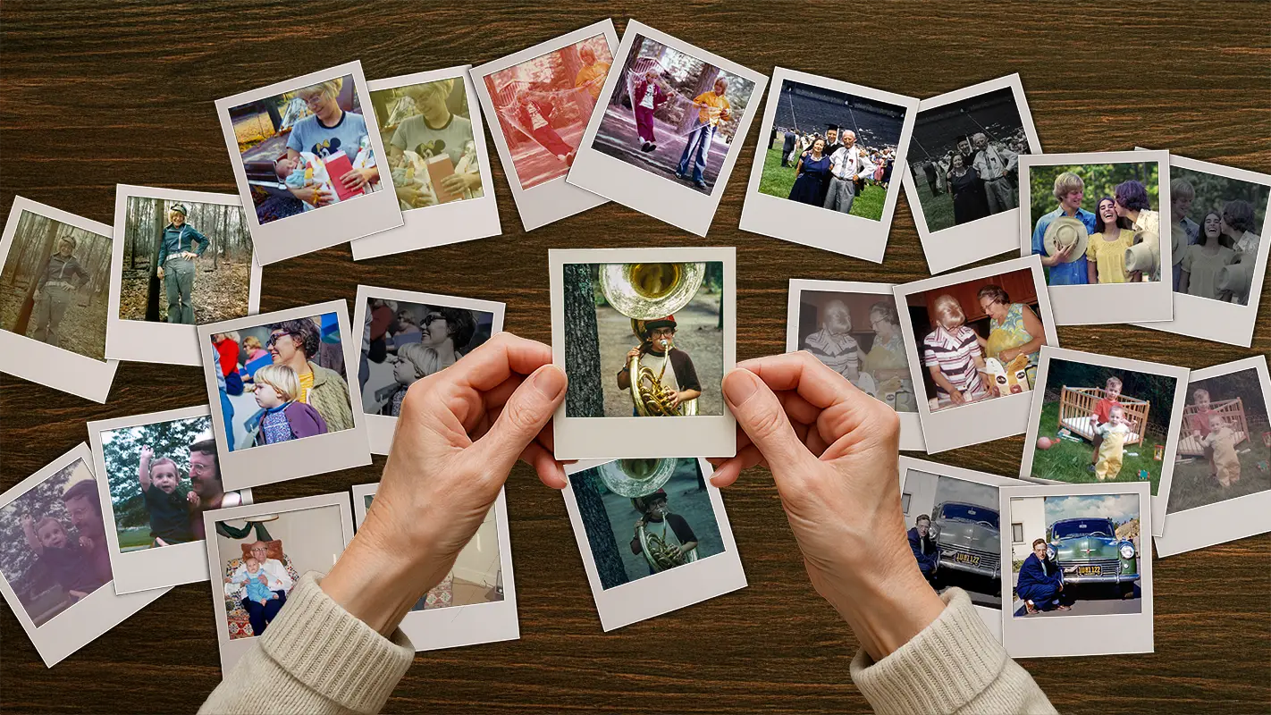 Hands holding a restored family photo surrounded by old Polaroids
